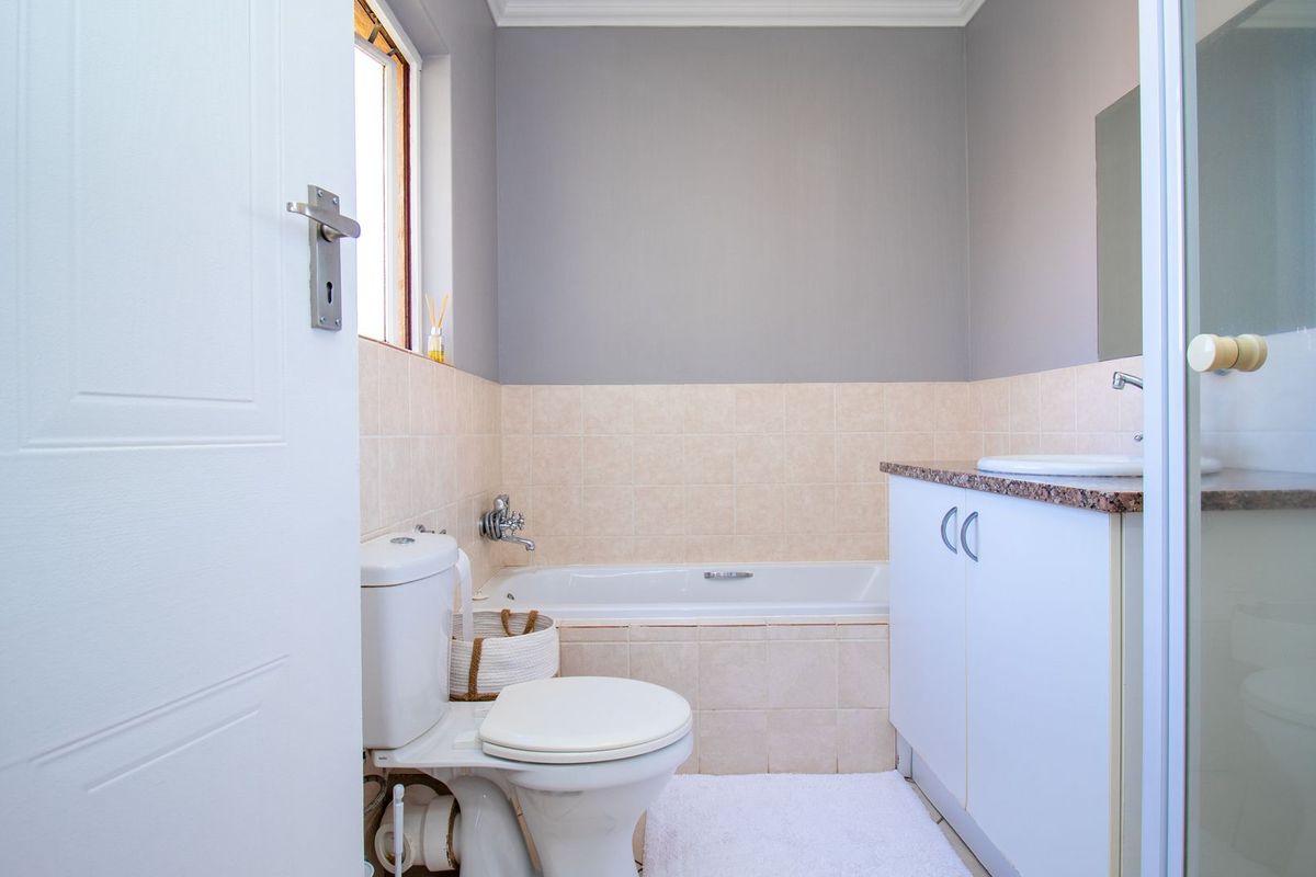 A functional bathroom featuring a built-in vanity with granite countertop, a bathtub, and a separate shower enclosure with neutral wall finishes.