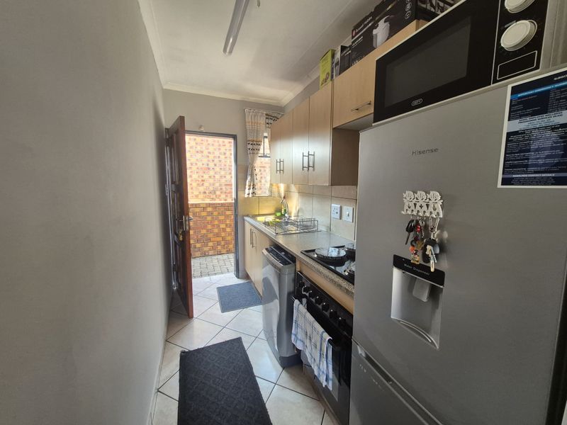 A functional scullery area featuring built-in cabinetry, a sink, and space for appliances, with direct access to an exterior courtyard.