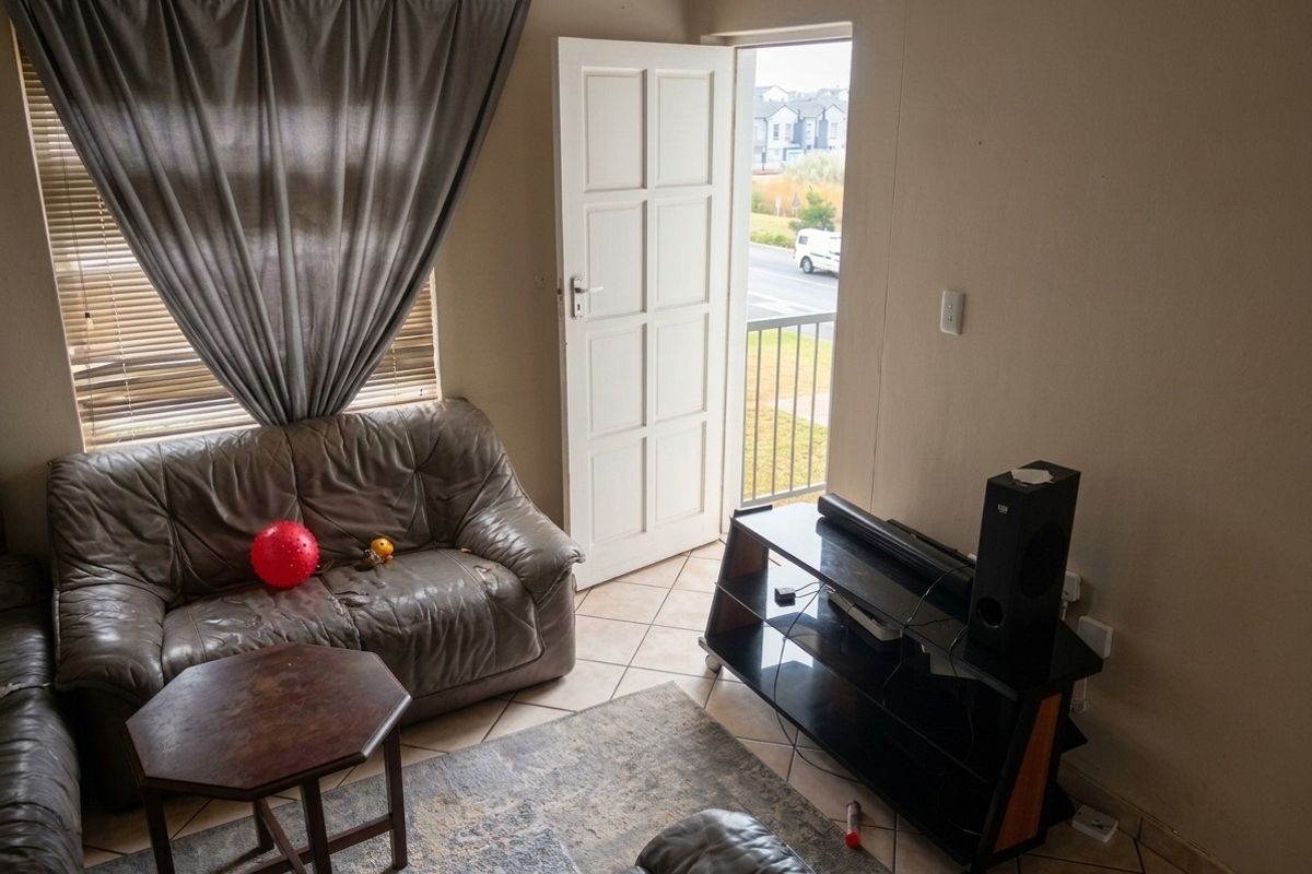 A living room area featuring tiled flooring and direct access to an exterior balcony through a panelled door.