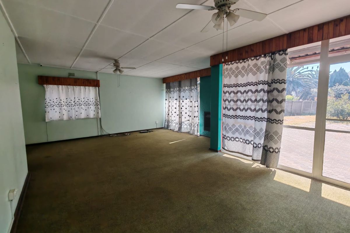 Spacious living room featuring a fireplace, ceiling fans, and large sliding glass doors providing access to the outdoor area.