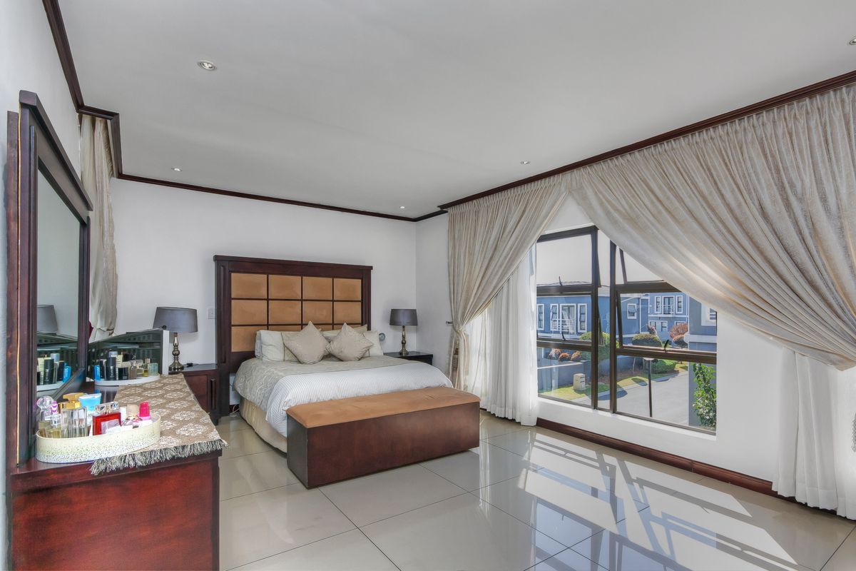 Spacious bedroom featuring large windows with curtains, tiled flooring, and recessed ceiling lighting, offering a bright and comfortable living space.