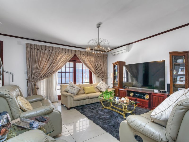 A comfortable living room featuring tiled flooring, a wall-mounted air conditioning unit, and large windows with access to the exterior.