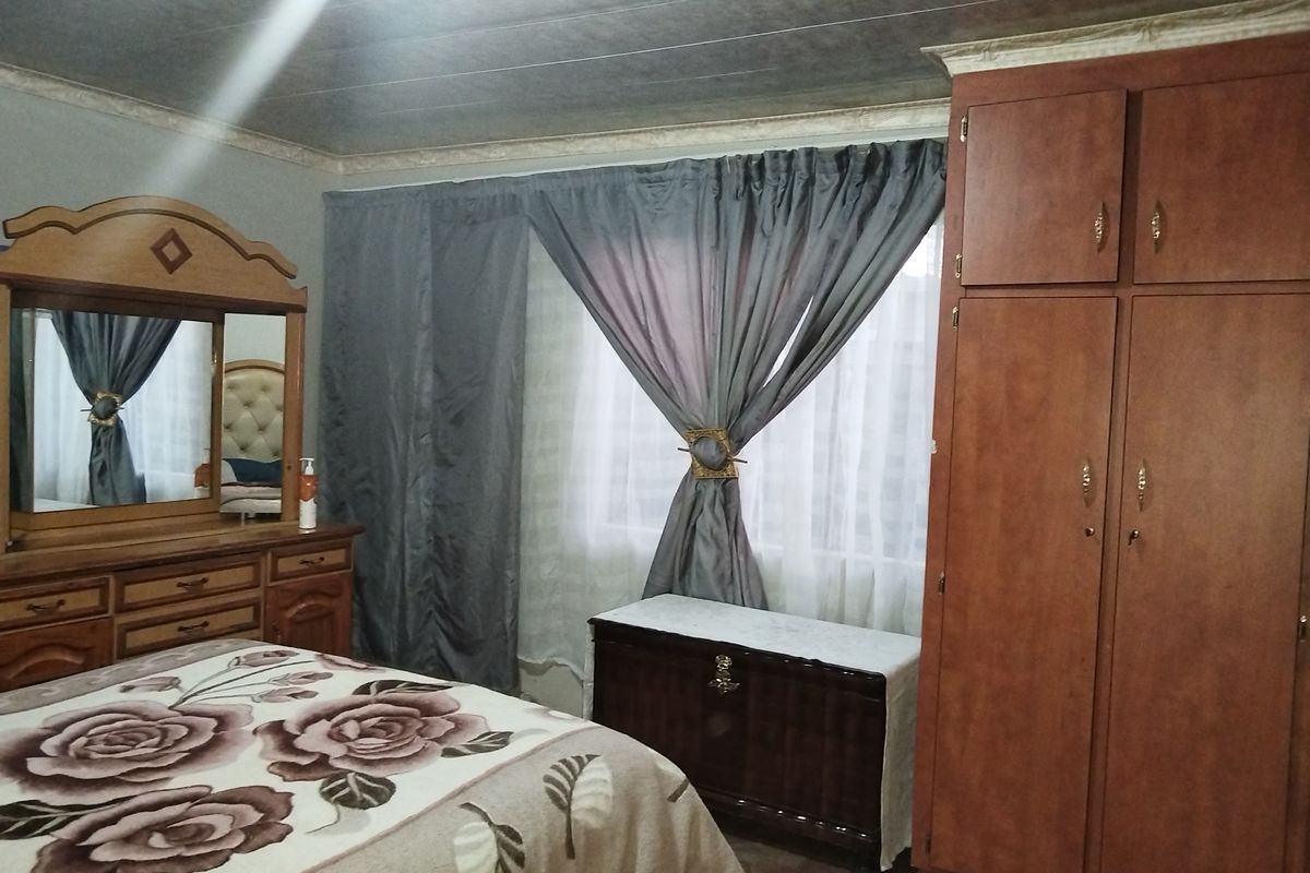 A bedroom featuring a built-in wooden wardrobe and ceiling panel finishes, providing functional storage space.