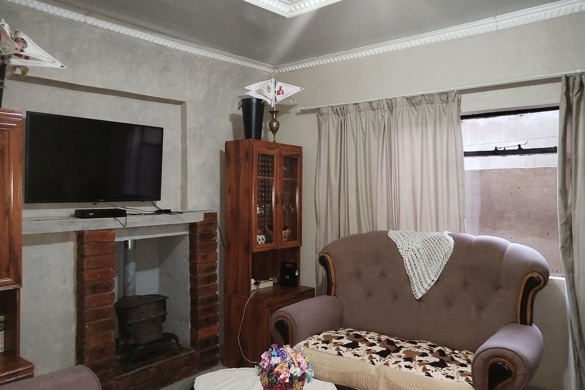 A cozy living room featuring an exposed brick fireplace with a cast iron stove and decorative ceiling cornicing.
