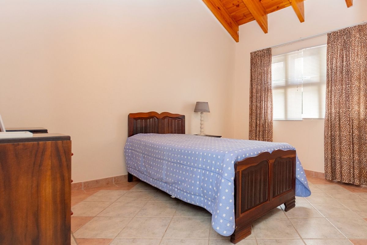 A bedroom featuring a vaulted ceiling with exposed timber rafters and tiled flooring, providing a rustic and spacious atmosphere.
