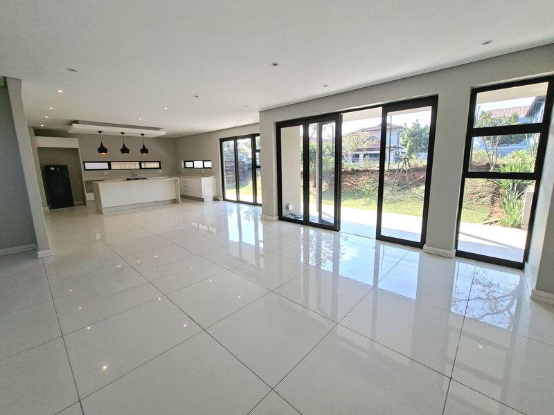 Spacious open-plan living and kitchen area featuring polished porcelain tiles, modern cabinetry, and large aluminium sliding doors opening to the garden.