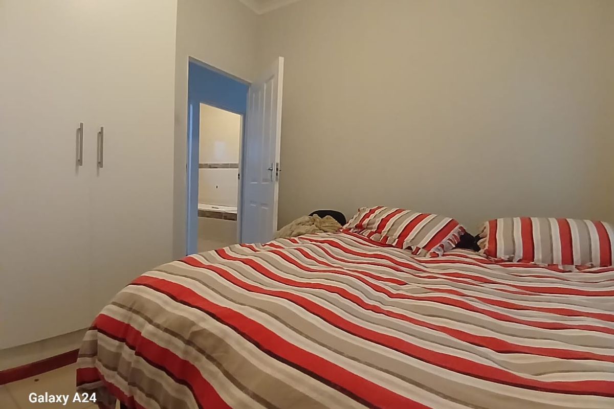 A bedroom featuring built-in cupboards and coved cornicing, with an adjoining bathroom visible through the doorway.