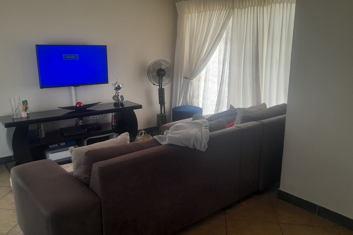 A living room area featuring tiled flooring and window treatments, providing a functional space for relaxation.