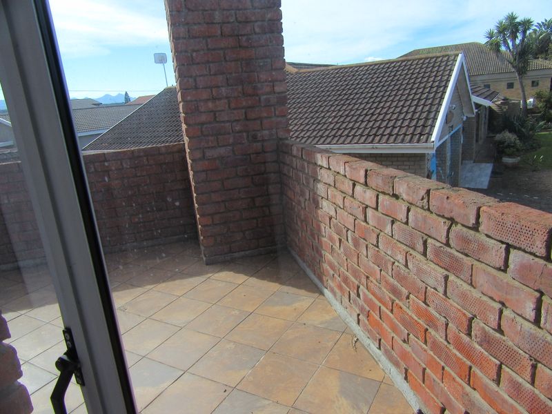 An elevated balcony featuring a brick chimney and low brick parapet walls with tiled flooring, offering an open outdoor space.
