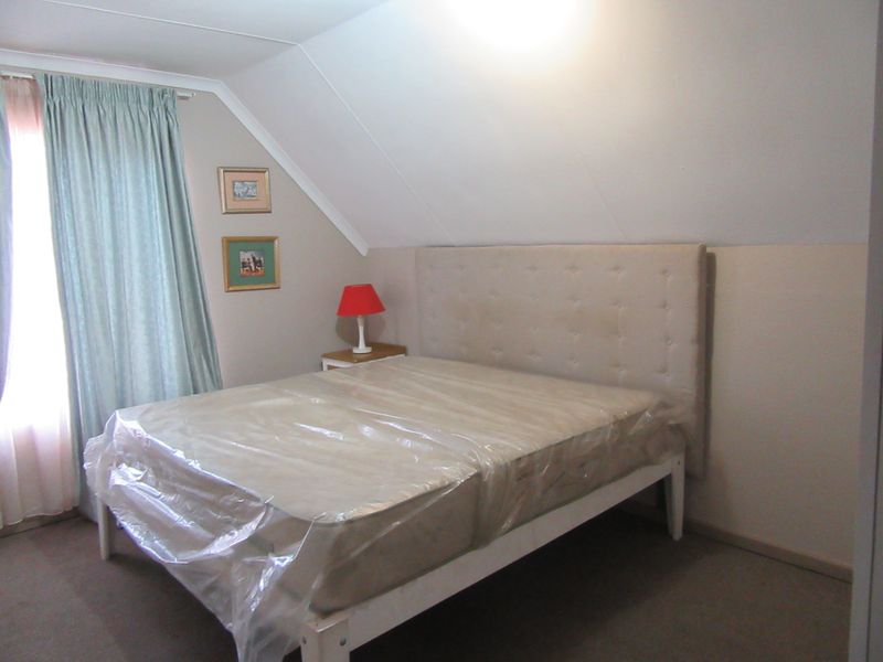 A bedroom featuring a sloped ceiling and carpeted flooring, providing a cozy and functional sleeping space.