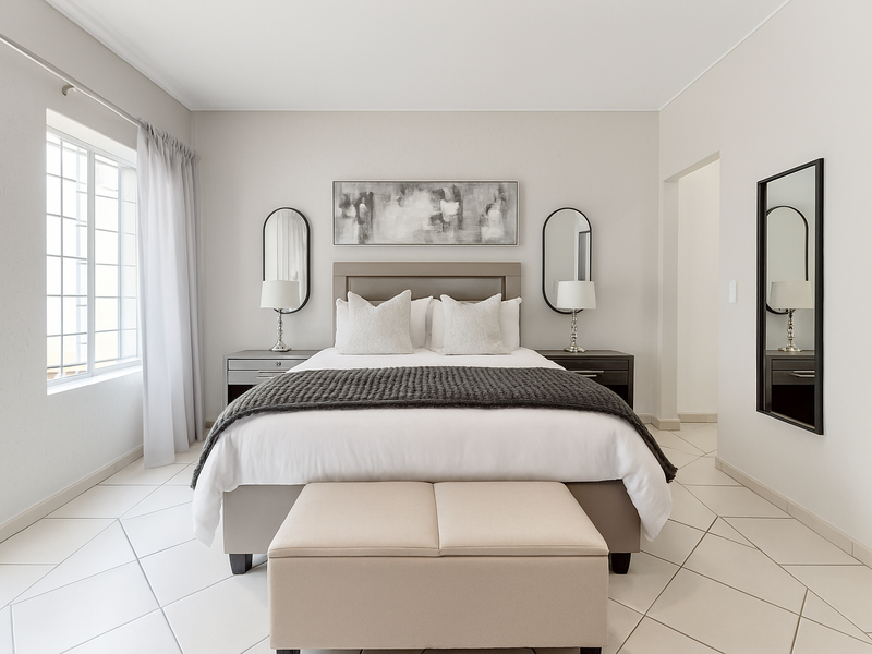 A well-maintained bedroom featuring neutral tones, tiled flooring, and a large window allowing for natural light.