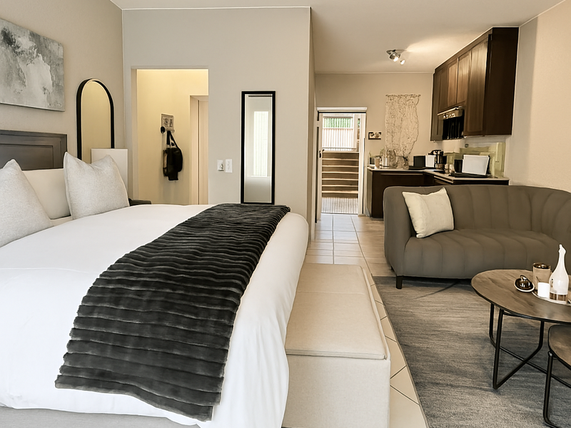 Open-plan studio apartment featuring a bedroom area, integrated kitchenette with dark cabinetry, and tiled flooring throughout.