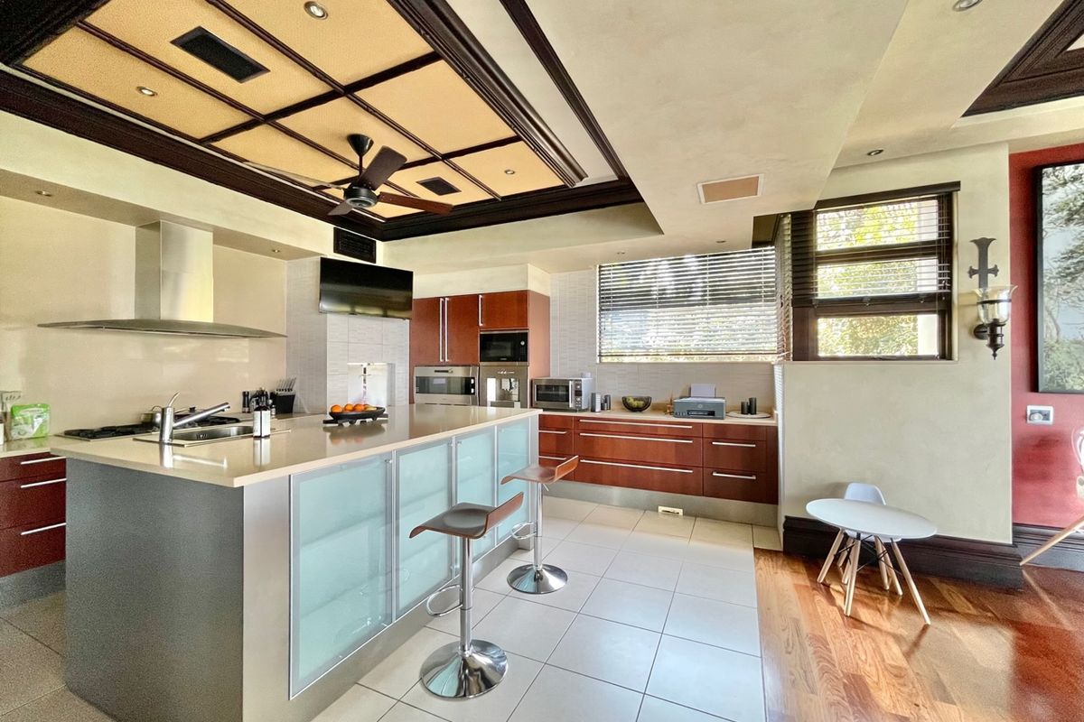 Modern kitchen featuring a large central island with breakfast bar, built-in stainless steel appliances, and a decorative coffered ceiling with recessed lighting.