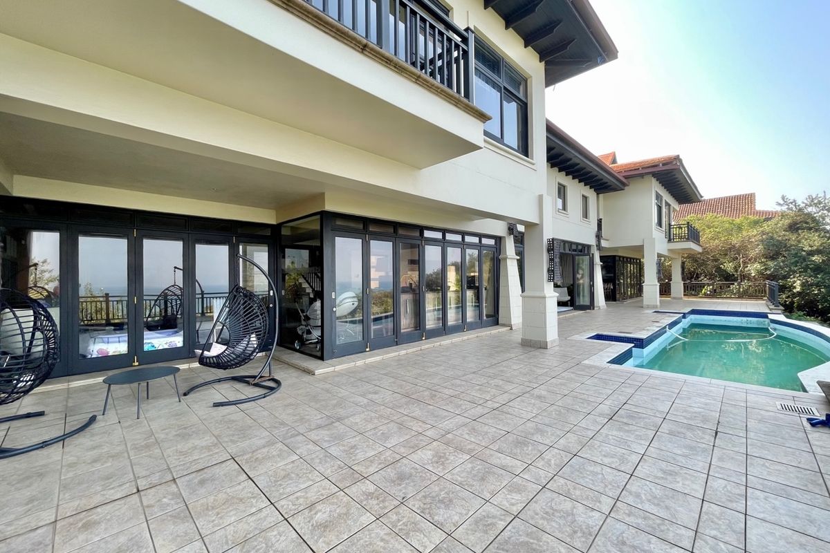 Spacious rear patio featuring tiled flooring, large glass folding doors, and a swimming pool, offering a seamless transition between indoor and outdoor living areas.