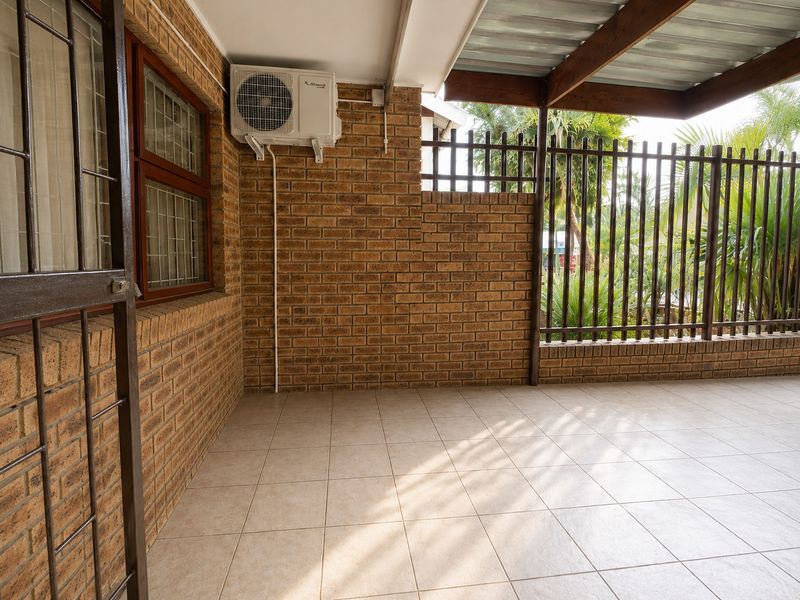 A covered patio area featuring face brick walls, tiled flooring, and a timber pergola, providing a functional outdoor space for relaxation.