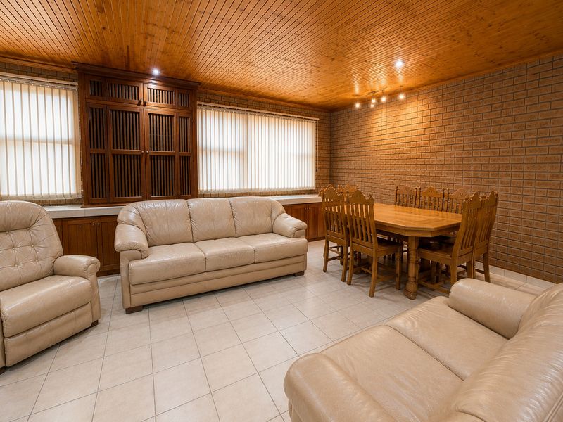 Spacious open-plan living and dining area featuring a timber-clad ceiling, face brick walls, and extensive built-in wooden cabinetry.