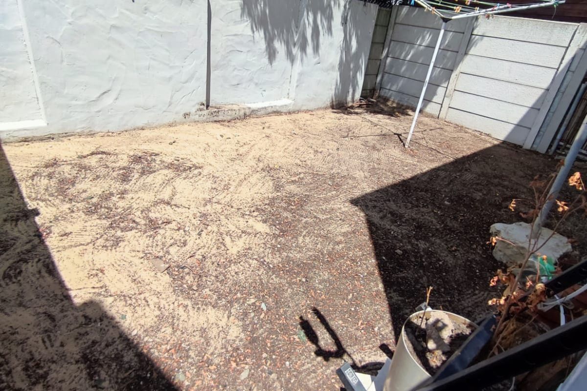A private rear courtyard area featuring a precast concrete boundary wall with electric fencing and a rotary clothesline.
