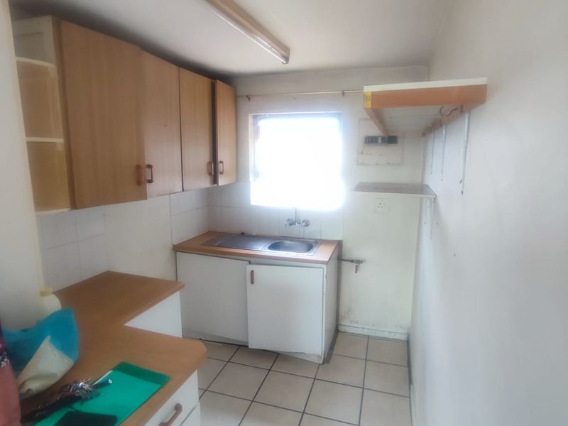 A compact, dated kitchen featuring laminate countertops, built-in cabinetry, and tiled flooring, offering a functional space ready for modernization and renovation.