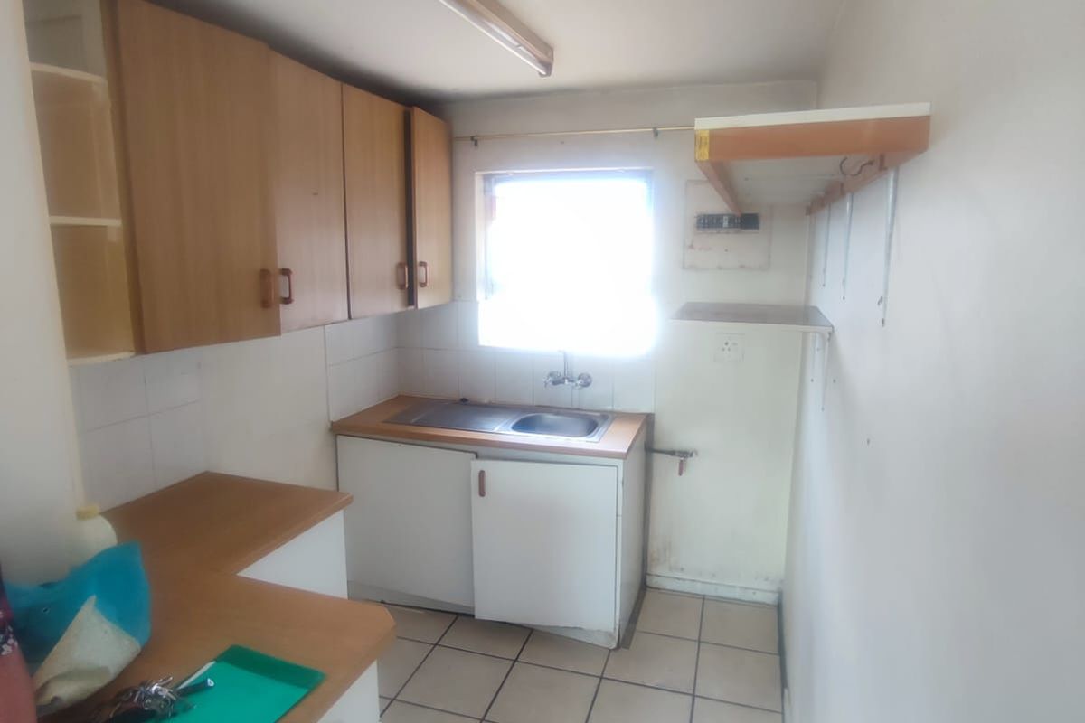 A compact, dated kitchen featuring laminate countertops, built-in cabinetry, and tiled flooring, offering a functional space ready for modernization and renovation.