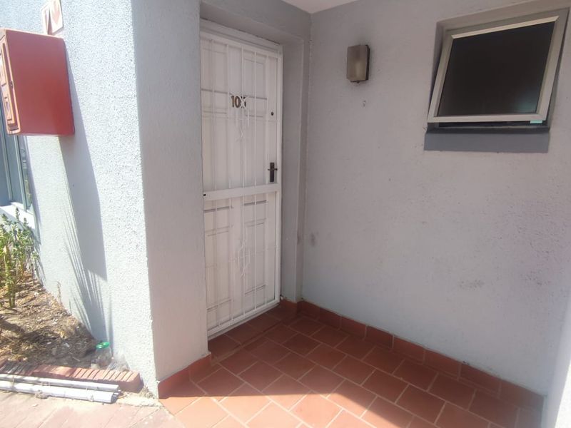 A functional apartment entrance featuring a security gate, tiled flooring, and a wall-mounted fire hose reel.