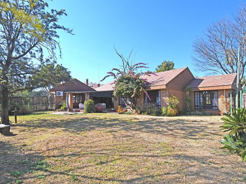 A view of the rear exterior of the house, featuring a brick facade, tiled roof, and a spacious garden area.