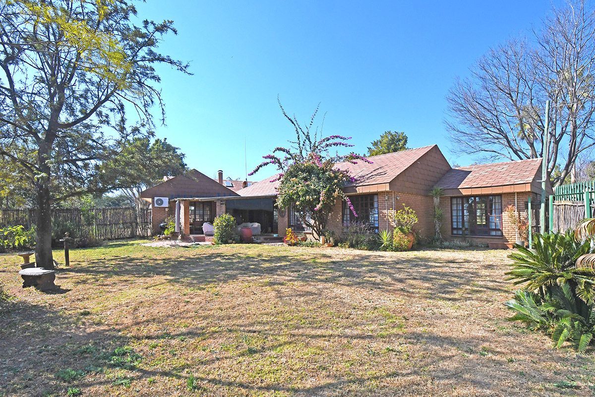 A view of the rear exterior of the house, featuring a brick facade, tiled roof, and a spacious garden area.