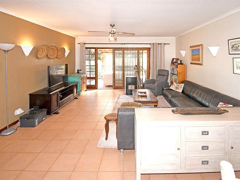 Spacious open-plan living area featuring tiled flooring, ceiling fan, and large sliding glass doors providing direct access to the outdoor patio.
