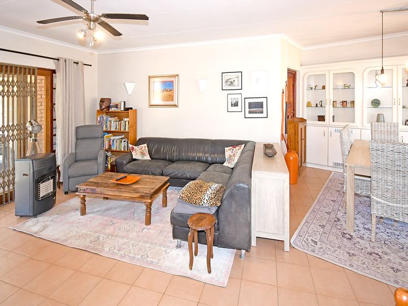 Open plan living and dining area featuring tiled flooring, a ceiling fan, and built-in display cabinetry.