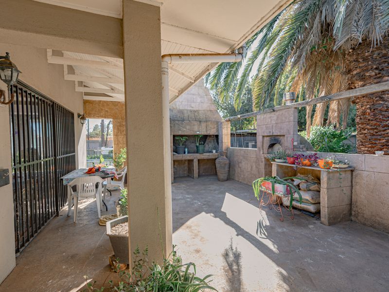 Covered outdoor patio area featuring a built-in braai and prep counter, providing a functional space for outdoor entertaining and dining.