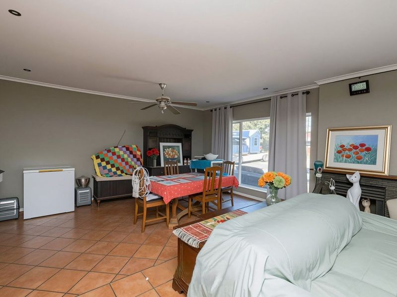 Spacious living and dining area featuring tiled flooring, a ceiling fan, and a built-in fireplace, offering a versatile layout for family living.