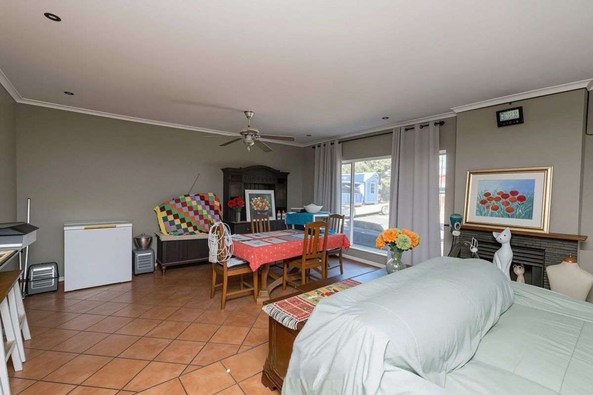 Spacious living and dining area featuring tiled flooring, a ceiling fan, and a built-in fireplace, offering a versatile layout for family living.