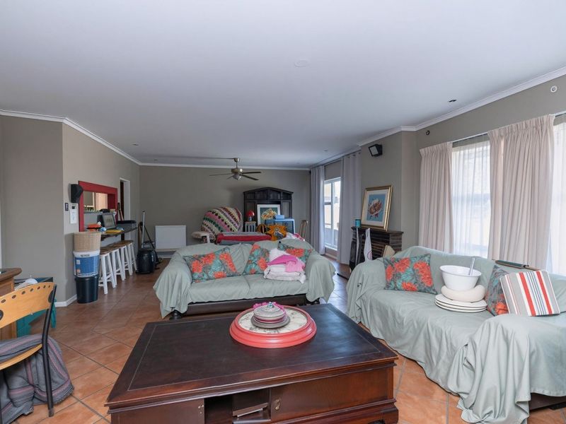 Spacious living room featuring tiled flooring, a ceiling fan, and a convenient serving hatch connecting to the kitchen area.