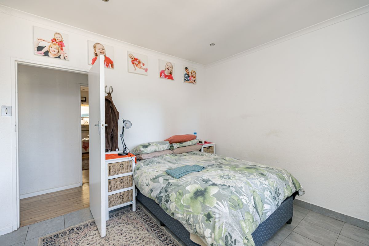 A functional bedroom featuring tiled flooring, coved ceilings, and recessed lighting, providing a clean and neutral space for rest.