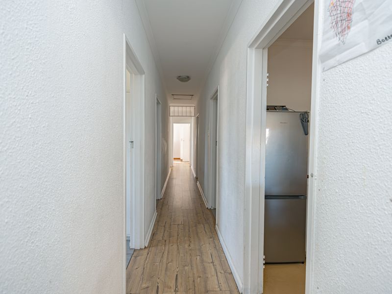 A clean, neutral hallway featuring wood-look tile flooring and access to multiple rooms, providing a functional transition space within the home.