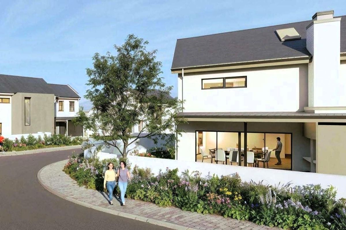 Modern residential exterior featuring a pitched roof, chimney, and large sliding glass doors opening to a landscaped garden and paved walkway.