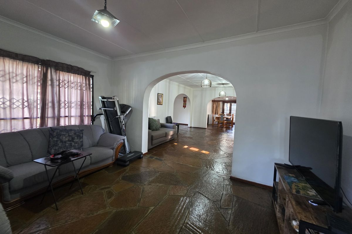 Spacious living area featuring distinctive stone flooring and classic architectural archways connecting to the dining space.
