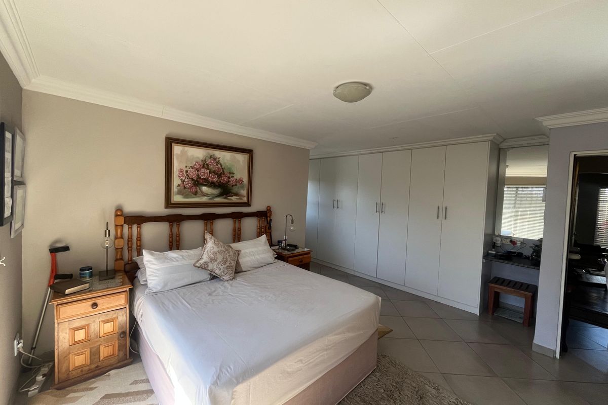 Spacious bedroom featuring extensive built-in cupboards, tiled flooring, and a dedicated vanity area with neutral wall finishes.