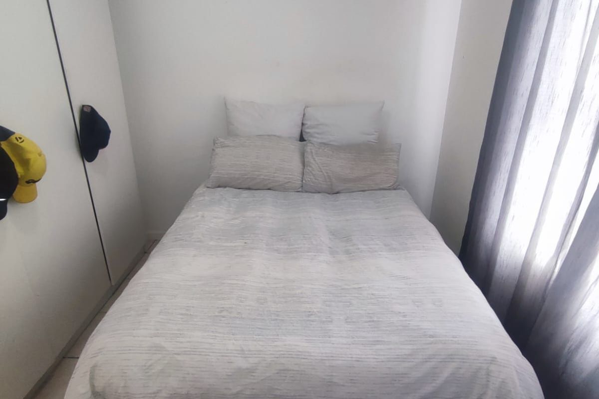 A compact bedroom featuring tiled flooring and a built-in wardrobe, providing functional storage space.
