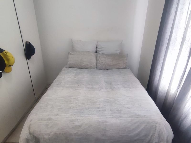 A compact bedroom featuring tiled flooring and a built-in wardrobe, providing functional storage space.