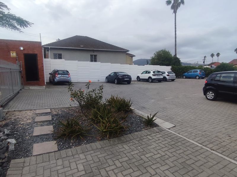 A paved parking area for the apartment complex featuring a secure boundary wall and metal gate access.