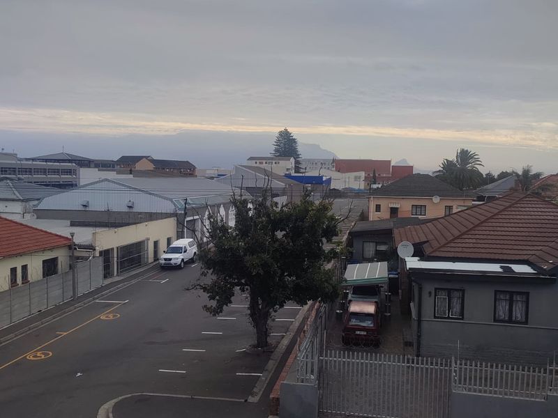 An elevated view overlooking a suburban street, surrounding residential properties, and local infrastructure under a cloudy sky.