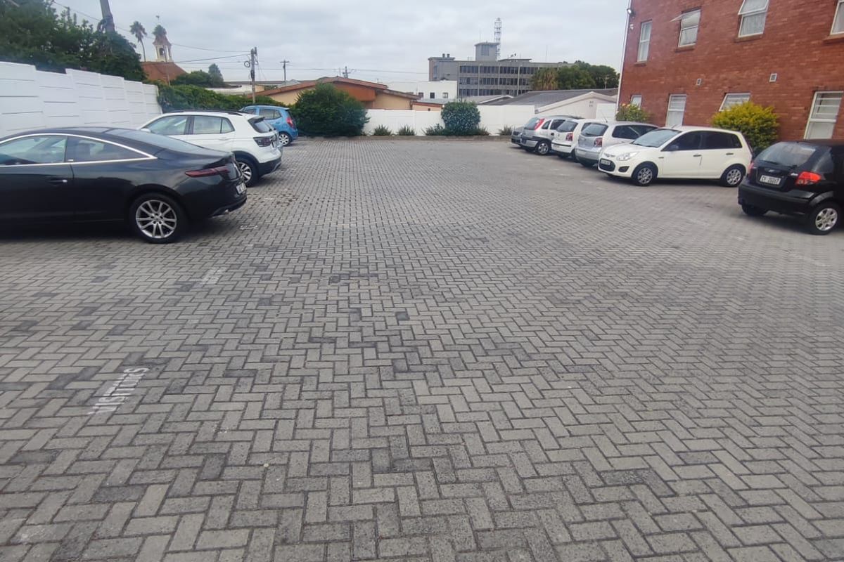 A paved parking area located at the rear of the apartment building, providing designated parking spaces for residents.
