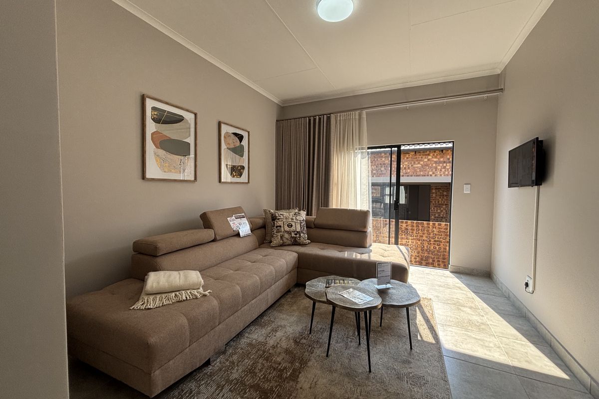 A well-maintained living room featuring neutral wall tones, tiled flooring, and a sliding glass door providing access to the exterior.