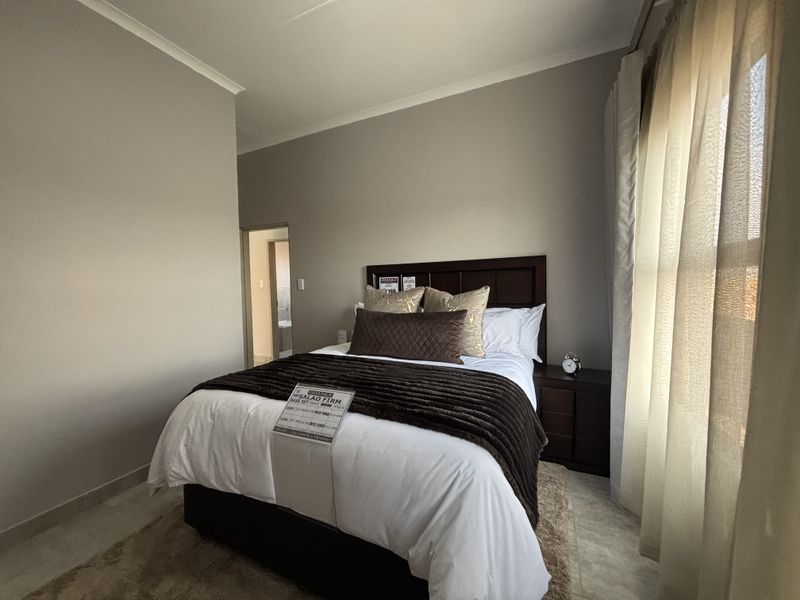 A well-maintained bedroom featuring neutral wall tones, tiled flooring, and coved ceiling details, with an adjoining doorway leading to an en-suite bathroom.