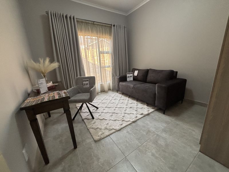 A well-maintained living area featuring neutral tiled flooring, large sliding doors with curtain tracks, and a clean, modern aesthetic.