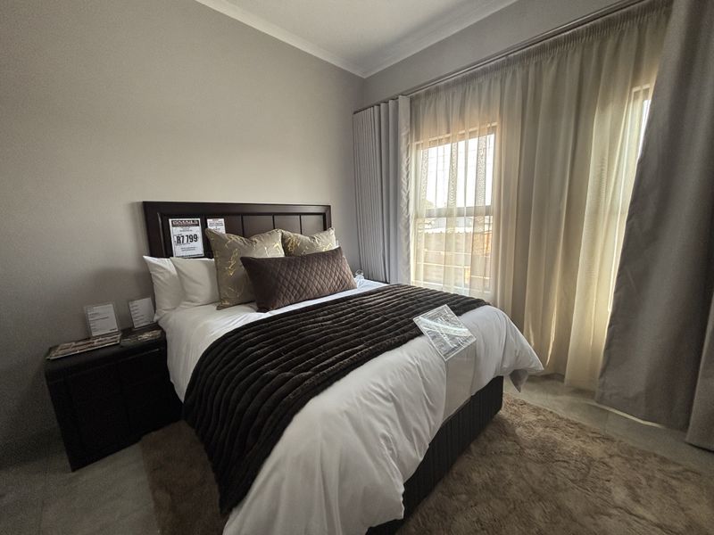 A well-maintained bedroom featuring neutral wall tones, large windows with fitted curtain tracks, and classic coving detail.