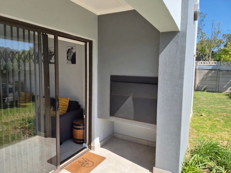 Covered patio area featuring a built-in braai and sliding glass door access to the interior living space.