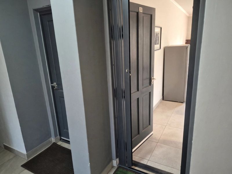 An apartment entrance area featuring tiled flooring and dark-toned internal doors, providing access to the main living space.