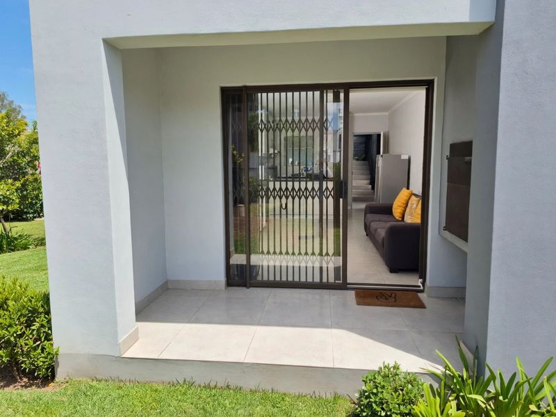A covered patio area featuring tiled flooring and a secure sliding gate, providing direct access to the interior living space.