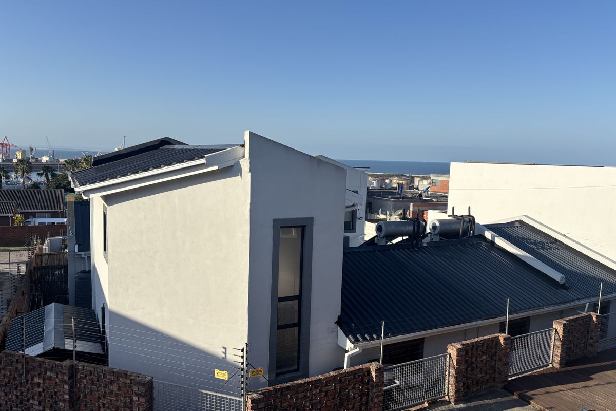 An elevated view of the property roofline, featuring modern metal roofing, solar water heating systems, and secure perimeter brick walling with electric fencing.